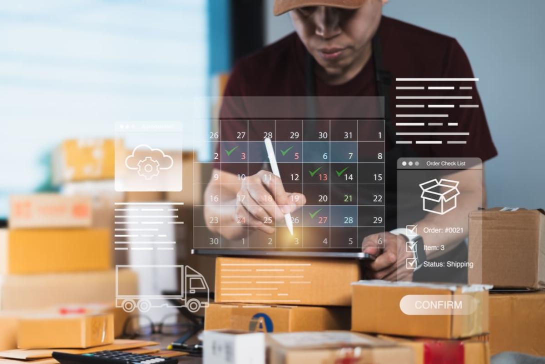 Pessoa com tablet organiza datas em um calendário digital flutuante cercada por pacotes, exemplificando o uso de um calendário para e-commerce.